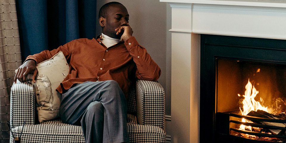 man sitting by fireplace